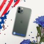 A green iPhone in a HR CrystalShield iPhone® Case rests on a surface, partially covered by an American flag. Next to the flag, blue flowers and red star-shaped confetti are scattered around the phone. A logo of "hasty rank" is on the phone case.