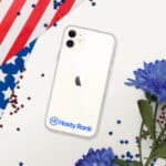 A HR CrystalShield iPhone® Case with a logo for "hasty rank" on an iphone lying on a surface. the background is decorated with an american flag and blue flowers, with scattered red and blue confetti.