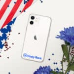 A HR CrystalShield iPhone® Case with a logo labeled "hasty rank" on the back, covering a white iphone with dual cameras, is displayed on a surface adorned with an american flag and blue flowers. red and blue confetti accent the scene.