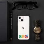 A flat lay of a desk with a white smartphone featuring a SEO Clear Case for iPhone®, a black notebook, a pen, sunglasses, and a gold watch, all arranged neatly on a dark surface.
