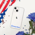 A HR CrystalShield iPhone® Case with a logo on a white iphone, surrounded by red, white, and blue star confetti, part of an american flag, and blue flowers on a white surface.