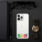 An SEO Clear Case for iPhone® with "seo" in google's colors on its back, flanked by a black notebook, a pencil, sunglasses, and a gold watch, all arranged on a dark surface.