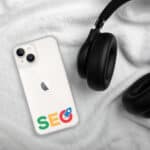 An iPhone® with a custom "SEO Clear Case for iPhone®" logo on its case is placed on a white fluffy blanket, next to a pair of black over-ear headphones, implying a setting of digital work or leisure related to search engine optimization.