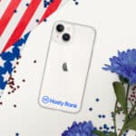 A smartphone with a HR CrystalShield iPhone® Case and a logo, resting on a surface decorated with a u.s. flag and blue flowers, with red and blue star-shaped confetti scattered around.