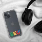 A SEO Clear Case for iPhone® displaying the apple logo and colorful "SEO" text lies on a soft white fabric, partially covered by black over-ear headphones. The phone's rear camera is visible at the top left.