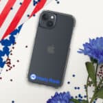 An HR CrystalShield iPhone® Case featuring a blue logo labeled "hasty rank" rests on a surface with a partial american flag and scattered red star confetti. Blue flowers are visible in the bottom right corner.