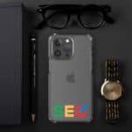 A SEO Clear Case for iPhone® with "seo" in colored letters on the back, next to a golden watch, black-rimmed glasses, a black notebook, and a pencil, all on a dark gray background.