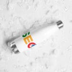 A white reusable SEO Stainless Steel Water Bottle with a colorful logo lies on a surface covered in ice cubes and water droplets, suggesting the bottle's cold insulation capabilities.