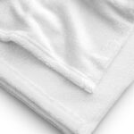 A close-up image of a neatly folded white HR Signature Towel. the texture of the towel is prominently displayed, highlighting its soft, fluffy fibers and the finely stitched hem along the edge. the background is uniformly white.