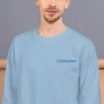 A man wearing a light blue long-sleeve HR ChillCozy Sweatshirt with the logo "hr hasty rank" on the left side of the chest. he appears calm with a slight, closed-lipped smile, in a beige background.