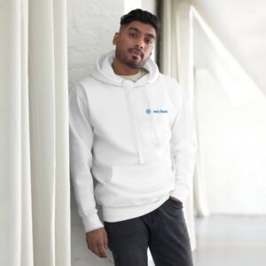 A man of south asian descent stands in a white room beside a column, wearing a HR CozyBlend Hoodie with a "unity rank" logo and dark pants, looking calmly at the camera.