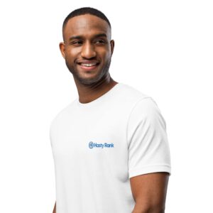 A cheerful black man wearing a white HR PrimeStyle Tee with a small "hasty rank" logo on the chest, smiling and standing against a plain white background. his stance is relaxed and his expression is friendly.