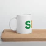 SEO White Glossy Mug with a green and orange letter 's' logo on its side, placed on a wooden board against a plain, light grey background.