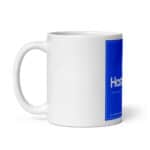 A HR Cheerful Brew Mug with a glossy finish features a bold blue label on the side. The label includes white text that reads "hastro" at the top and smaller text underneath. The mug handle is on the left side and it's set against a white background.