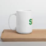 A SEO White Glossy Mug with a green and orange letter "s" logo on it, placed on a wooden cutting board against a light gray background.