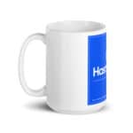 A white ceramic HR Cheerful Brew Mug with a large blue rectangular label that includes the logo and text "hastel, a full-service company," plus a contact number, against a white background.